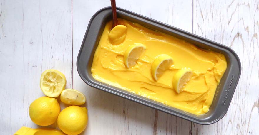 Mango sorbet in a tin pan, fresh lemon cut on top