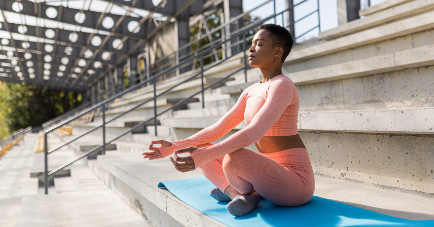 woman sitting doing yoga in stadium